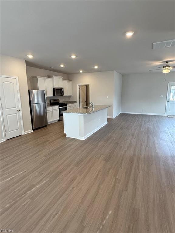 kitchen featuring visible vents, appliances with stainless steel finishes, open floor plan, white cabinetry, and wood finished floors