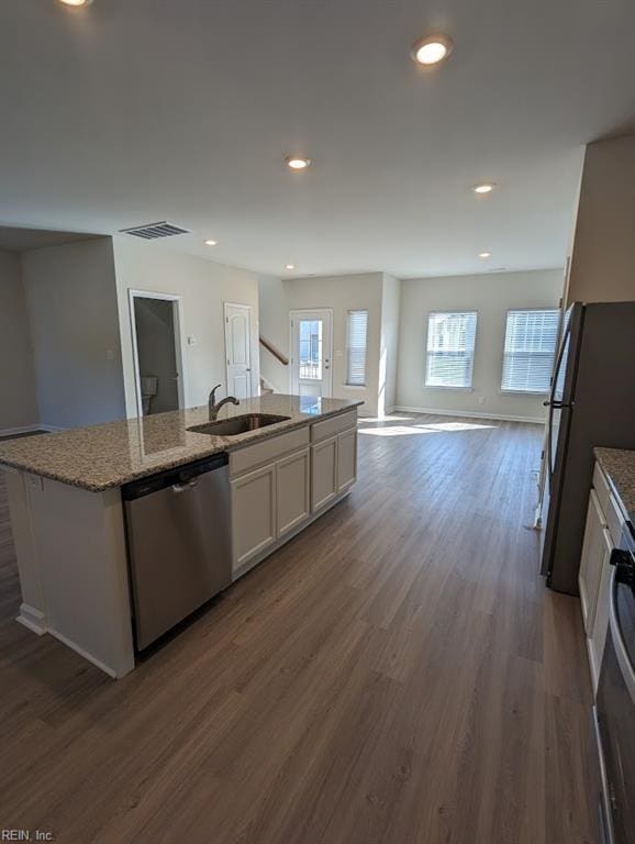 kitchen featuring a kitchen island with sink, dark wood-type flooring, a sink, visible vents, and stainless steel dishwasher