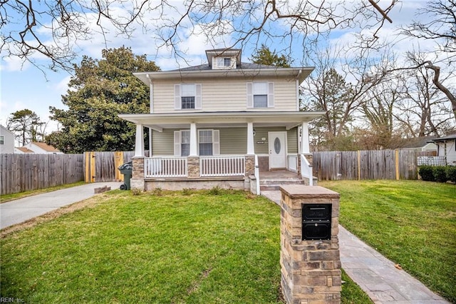 american foursquare style home featuring covered porch, fence, and a front lawn