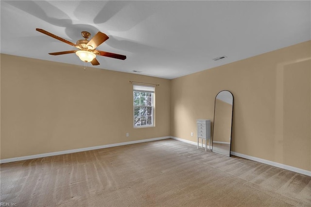 carpeted spare room featuring visible vents, ceiling fan, and baseboards