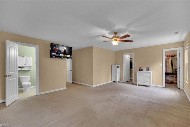 unfurnished bedroom featuring light carpet, ensuite bath, a walk in closet, and baseboards