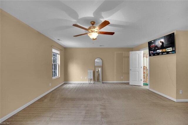 empty room featuring a ceiling fan, light colored carpet, and baseboards