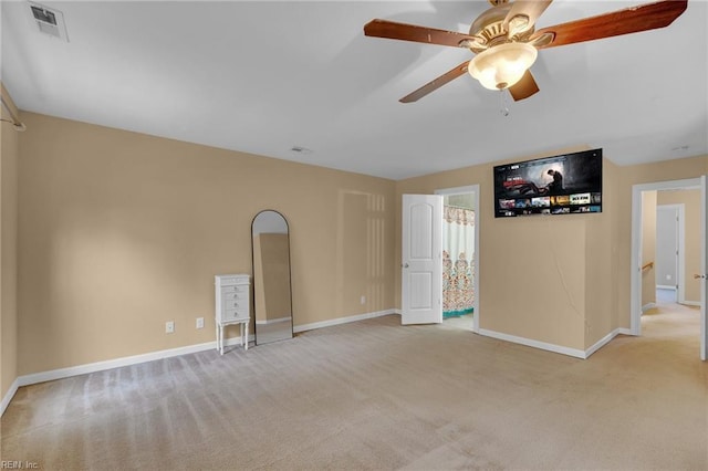 spare room featuring light colored carpet, ceiling fan, visible vents, and baseboards