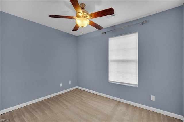 carpeted spare room featuring a ceiling fan, visible vents, and baseboards