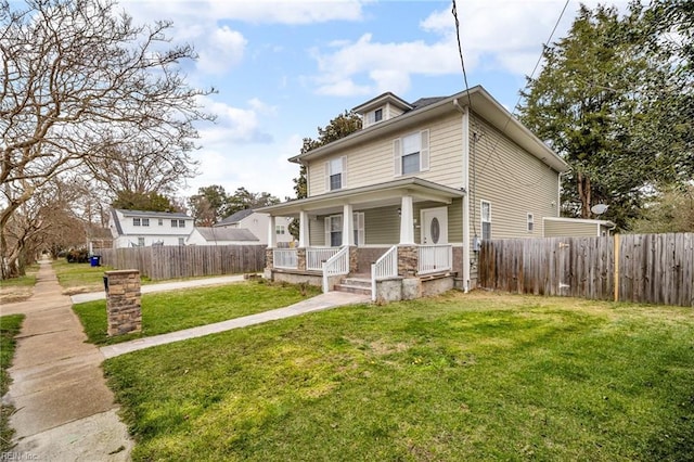 american foursquare style home featuring a porch, a front yard, and fence