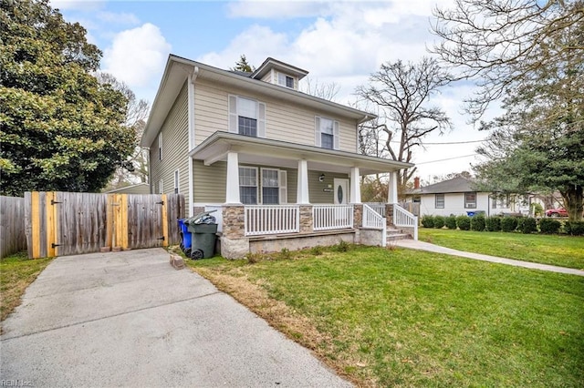 traditional style home featuring covered porch, a gate, fence, and a front lawn