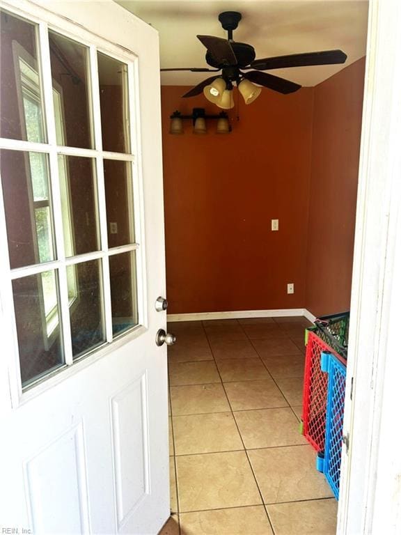 interior space featuring a ceiling fan, light tile patterned flooring, and baseboards