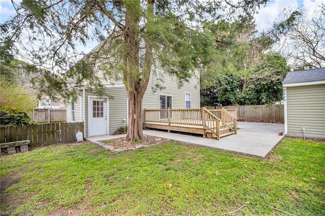 rear view of property with a lawn, a patio area, a fenced backyard, and a wooden deck