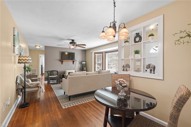 living room with ceiling fan with notable chandelier, hardwood / wood-style flooring, and baseboards