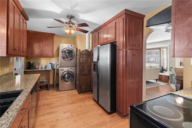 kitchen featuring stacked washer and dryer, light wood-style floors, refrigerator with ice dispenser, light stone countertops, and black range with electric cooktop