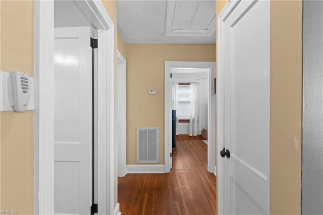 corridor featuring visible vents, baseboards, and wood finished floors