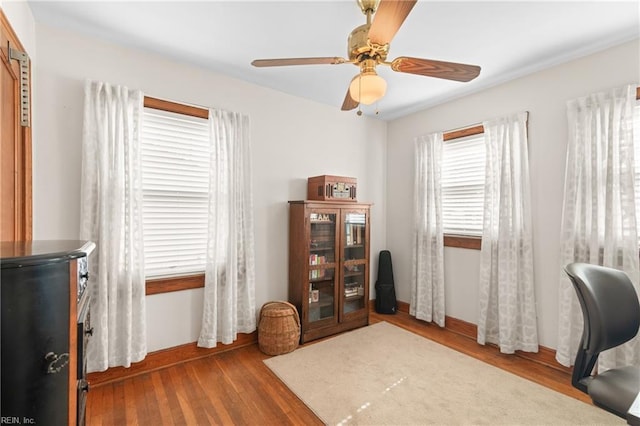 office area featuring a ceiling fan, baseboards, and wood finished floors