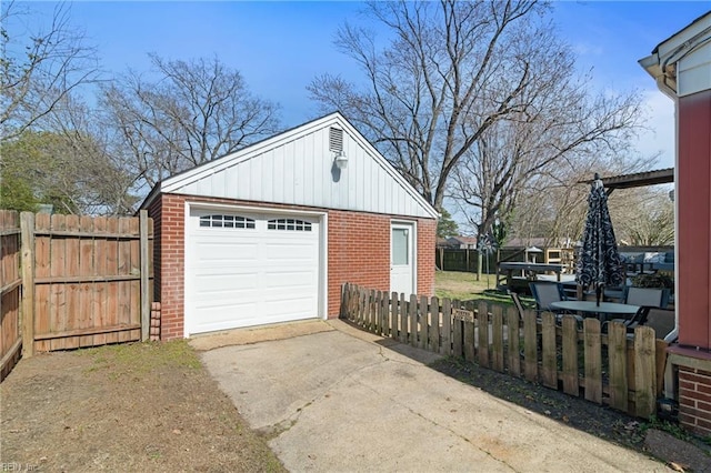 detached garage featuring driveway and fence