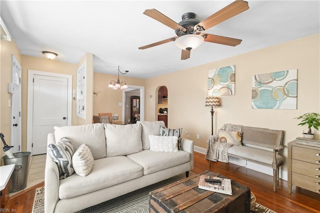 living room with ceiling fan with notable chandelier, arched walkways, baseboards, and wood finished floors