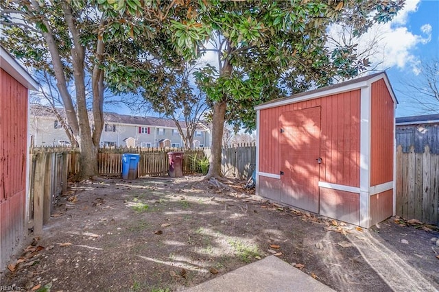 view of yard with a shed, a fenced backyard, and an outbuilding