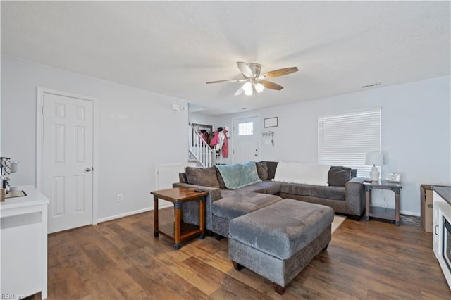 living area with dark wood-type flooring, visible vents, stairway, and a ceiling fan