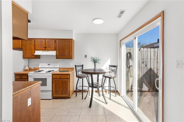 kitchen with electric stove, brown cabinetry, visible vents, and under cabinet range hood