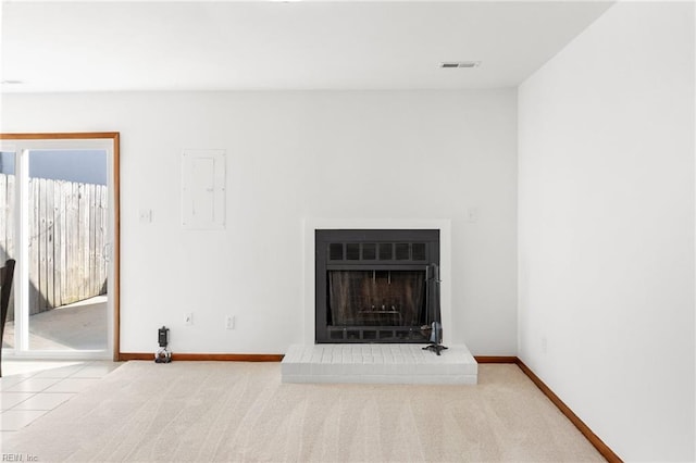 unfurnished living room featuring electric panel, visible vents, baseboards, a fireplace with raised hearth, and carpet