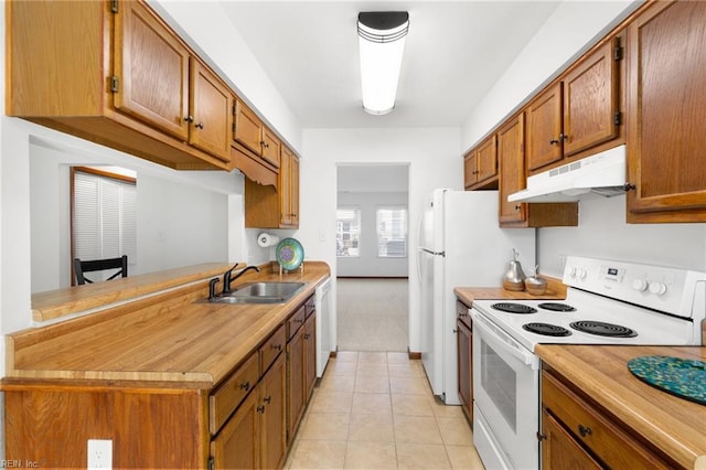 kitchen with light tile patterned flooring, under cabinet range hood, white appliances, a sink, and light countertops