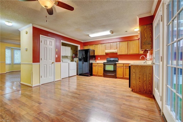 kitchen featuring under cabinet range hood, light wood-style floors, washer and dryer, light countertops, and black appliances