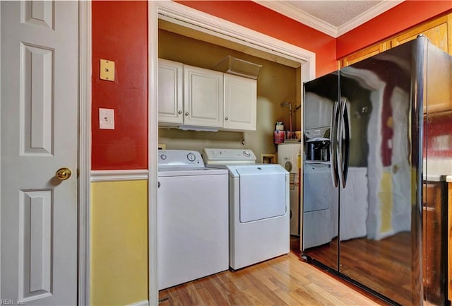 clothes washing area featuring ornamental molding, cabinet space, washer and clothes dryer, and light wood finished floors