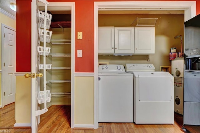 laundry area featuring light wood-type flooring, cabinet space, and washing machine and clothes dryer