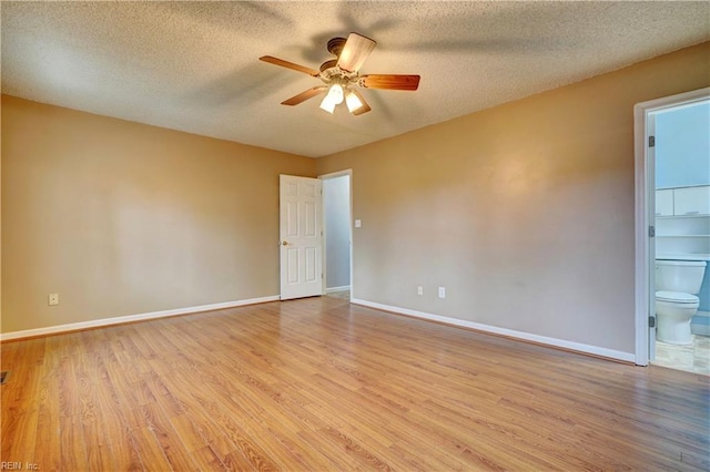 spare room with ceiling fan, a textured ceiling, light wood-type flooring, and baseboards