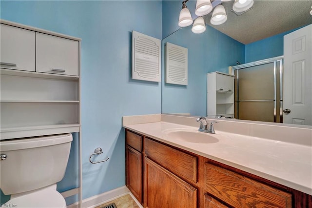 bathroom featuring a textured ceiling, toilet, vanity, baseboards, and a shower stall