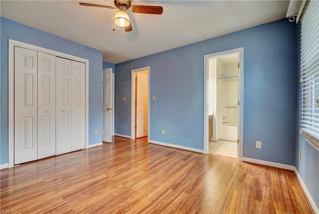 unfurnished bedroom featuring a closet, baseboards, light wood-style flooring, and a textured ceiling