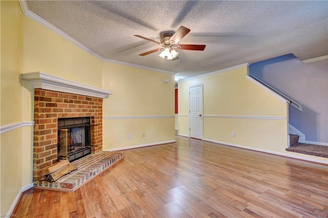 unfurnished living room with crown molding, a fireplace, a textured ceiling, wood finished floors, and baseboards