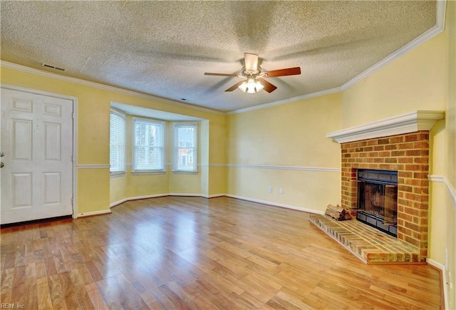 unfurnished living room featuring a brick fireplace, wood finished floors, visible vents, and crown molding