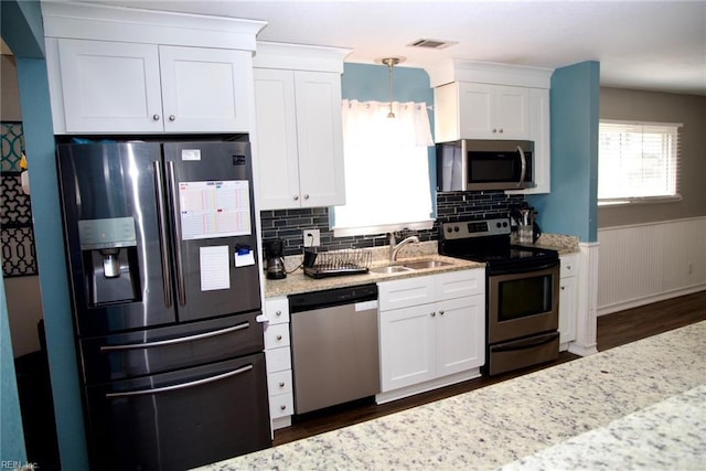 kitchen with appliances with stainless steel finishes, white cabinets, visible vents, and a sink