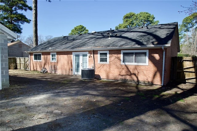 rear view of property with cooling unit, french doors, brick siding, and fence