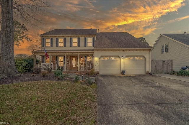 colonial house featuring a garage, covered porch, brick siding, and concrete driveway