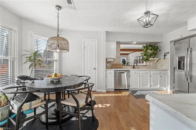 dining room with light wood-style floors, visible vents, and a notable chandelier