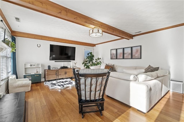 living room featuring ornamental molding, visible vents, beamed ceiling, and wood finished floors