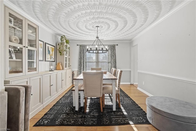 dining area with crown molding, an inviting chandelier, baseboards, and light wood-style floors