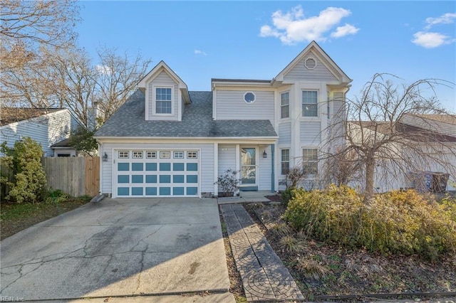 traditional-style home with driveway, roof with shingles, an attached garage, and fence