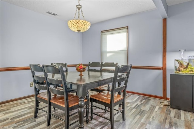 dining area featuring visible vents, baseboards, and wood finished floors