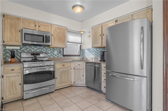 kitchen featuring stainless steel appliances, light brown cabinets, a sink, and tasteful backsplash