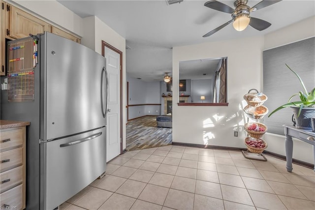 kitchen featuring light tile patterned floors, a fireplace, a ceiling fan, and freestanding refrigerator