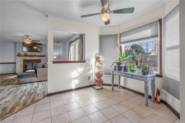 foyer entrance featuring a tile fireplace, light tile patterned flooring, a textured ceiling, and baseboards