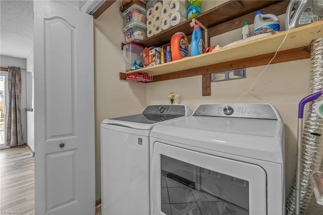 laundry area with laundry area, a textured ceiling, light wood-style floors, and washer and dryer