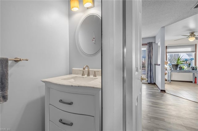 bathroom featuring visible vents, a ceiling fan, a textured ceiling, vanity, and wood finished floors