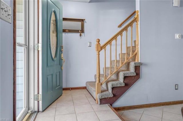 tiled foyer entrance with stairs, baseboards, and a wealth of natural light