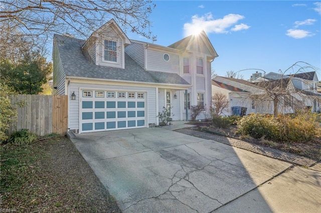 view of front facade with driveway, roof with shingles, an attached garage, and fence