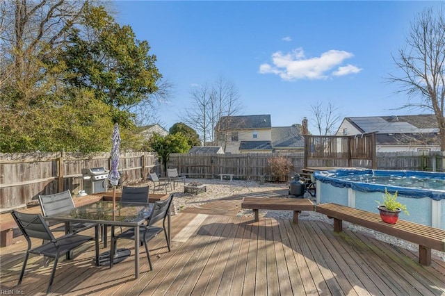 wooden terrace featuring a fire pit, a fenced in pool, a fenced backyard, a grill, and outdoor dining area