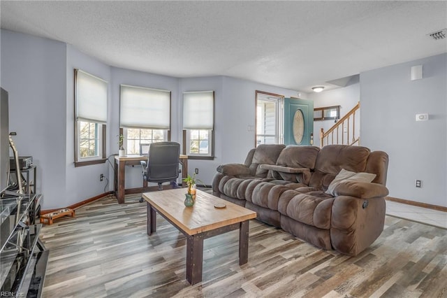 living area featuring a textured ceiling, baseboards, and light wood-style floors