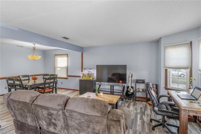 living area featuring baseboards, visible vents, and wood finished floors