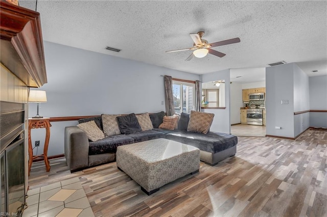 living area featuring ceiling fan, visible vents, and light wood-style floors